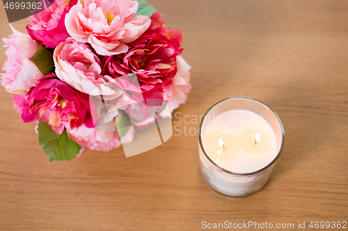 Image of burning fragrance candle and flower bunch on table