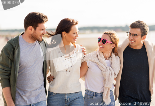 Image of happy friends walking along summer beach