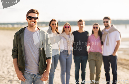 Image of happy man with friends on beach in summer