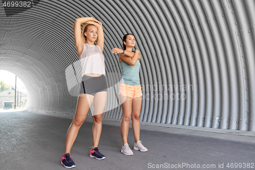 Image of women with fitness trackers stretching outdoors