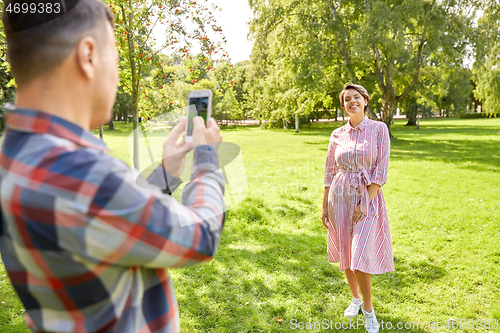 Image of couple photographing by smartphone in park