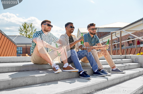 Image of happy male friends drinking beer on street