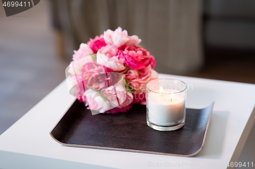 Image of burning fragrance candle and flower bunch at home