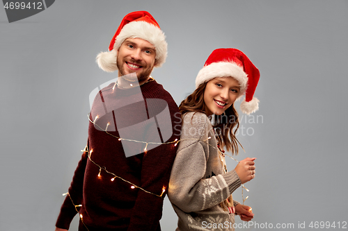 Image of happy couple in christmas sweaters and santa hats