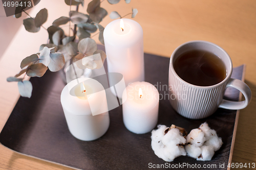Image of candles, tea and branches of eucalyptus on table