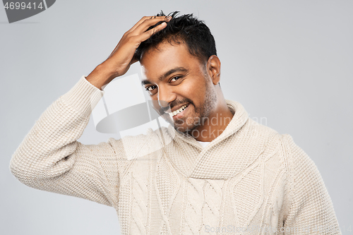 Image of indian man in knitted sweater touching his hair