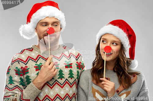 Image of couple with christmas party props in ugly sweaters