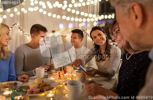 Image of happy family with smartphone at tea party at home
