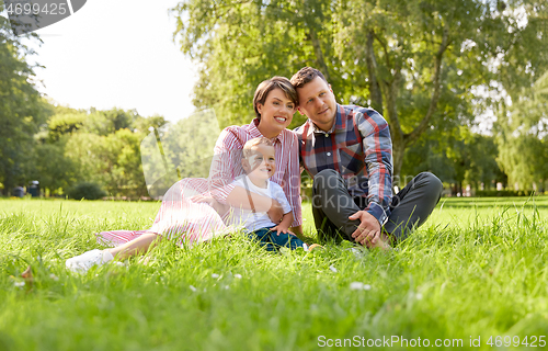 Image of happy family at summer park sitting on grass