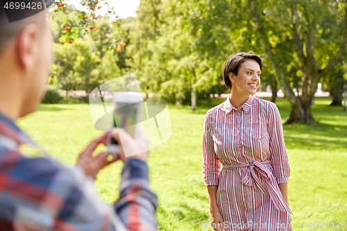 Image of couple photographing by smartphone in park