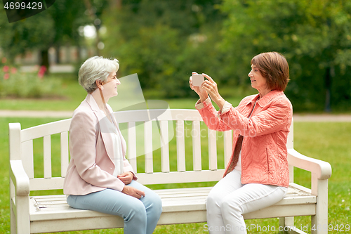 Image of senior woman photographing her friend at park