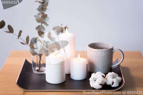 Image of candles, tea and branches of eucalyptus on table