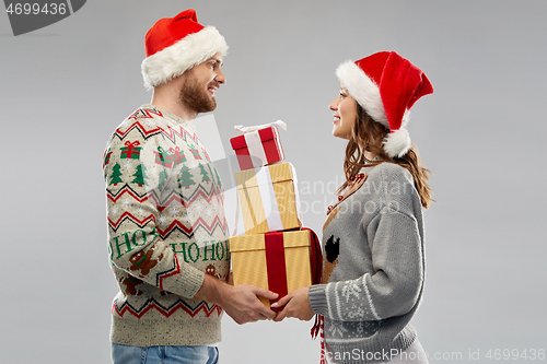 Image of happy couple in christmas sweaters with gifts