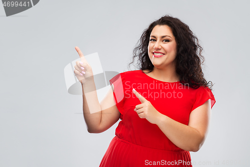Image of happy woman in red pointing fingers at something
