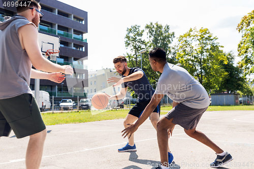 Image of group of male friends playing street basketball