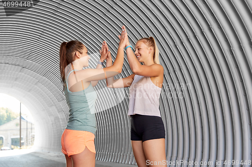 Image of happy women with fitness trackers making high five