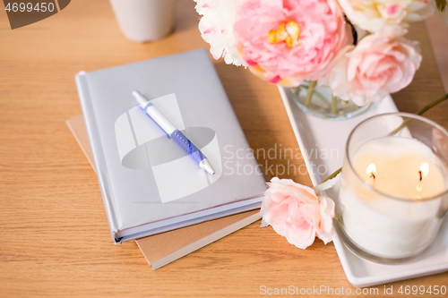 Image of burning candle and flower bunch on wooden table