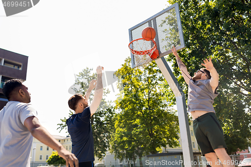 Image of group of male friends playing street basketball