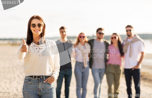 Image of woman with friends on beach showing thumbs up