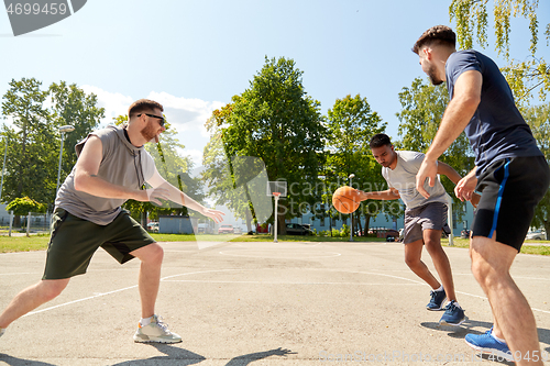 Image of group of male friends playing street basketball