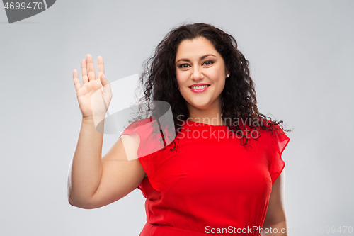 Image of happy woman in red dress waving hand