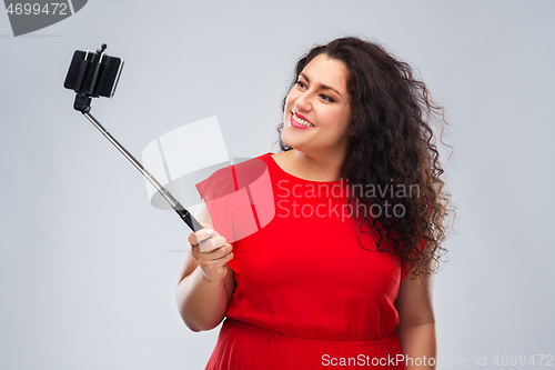 Image of woman taking picture by smartphone on selfie stick