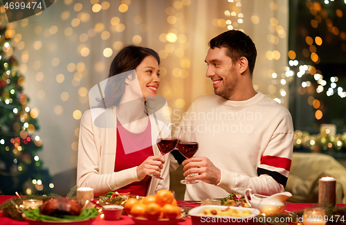 Image of happy couple drinking red wine at christmas dinner