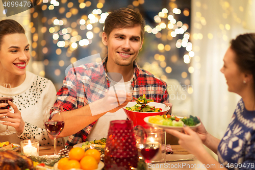 Image of happy friends having christmas dinner at home