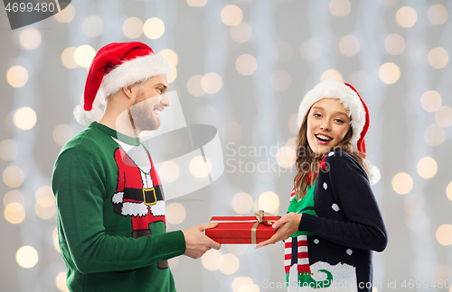 Image of happy couple in christmas sweaters with gift box