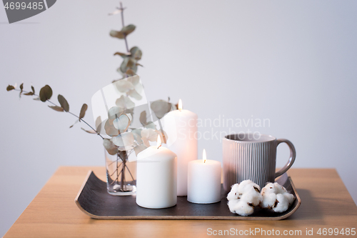 Image of candles, mug and branches of eucalyptus on table