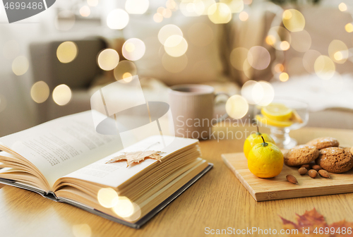 Image of book, lemon, tea and cookies on table at home
