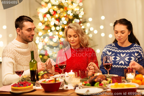 Image of friends praying before christmas dinner at home