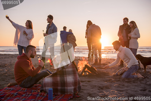 Image of Couple enjoying with friends at sunset on the beach