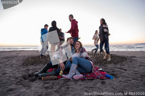 Image of Couple enjoying with friends at sunset on the beach