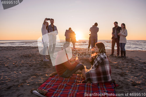 Image of Couple enjoying with friends at sunset on the beach