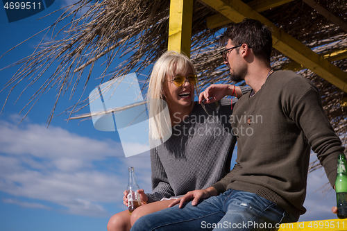 Image of young couple drinking beer together at the beach