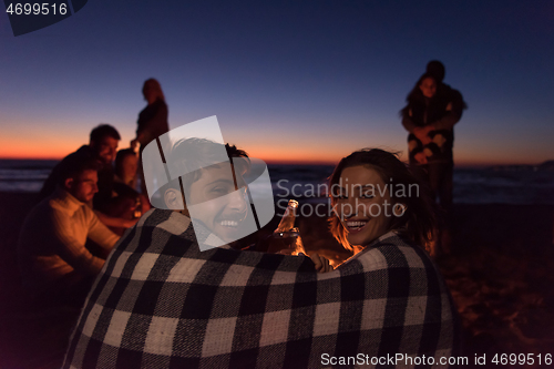 Image of Couple enjoying with friends at sunset on the beach