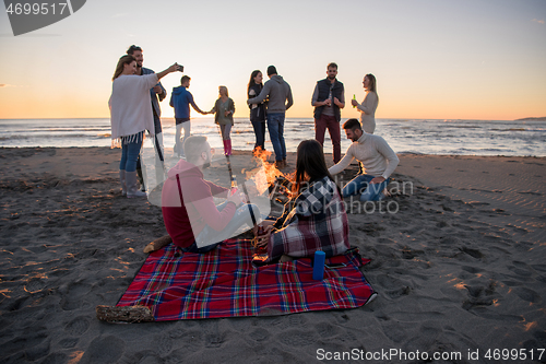 Image of Couple enjoying with friends at sunset on the beach