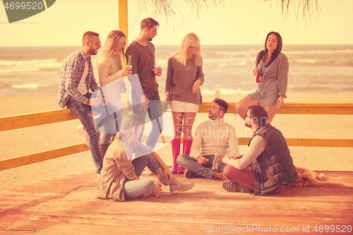 Image of Group of friends having fun on autumn day at beach