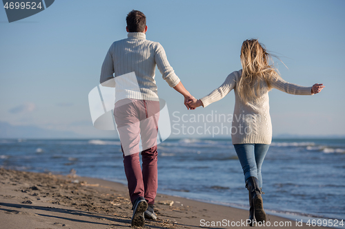 Image of Loving young couple on a beach at autumn sunny day