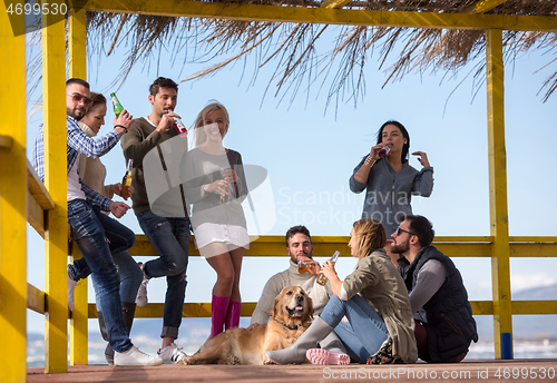 Image of Group of friends having fun on autumn day at beach