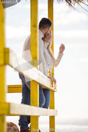 Image of young couple drinking beer together at the beach