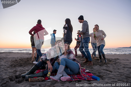 Image of Couple enjoying with friends at sunset on the beach