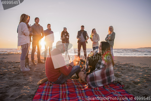 Image of Couple enjoying with friends at sunset on the beach