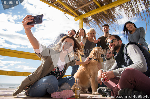 Image of Group of friends having fun on autumn day at beach