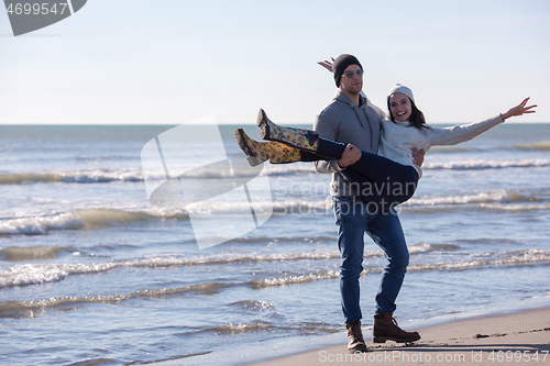 Image of Loving young couple on a beach at autumn sunny day