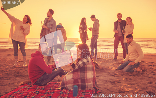 Image of Couple enjoying with friends at sunset on the beach