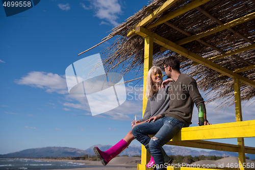 Image of young couple drinking beer together at the beach