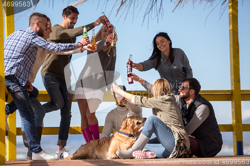 Image of Group of friends having fun on autumn day at beach