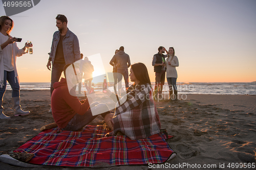 Image of Couple enjoying with friends at sunset on the beach